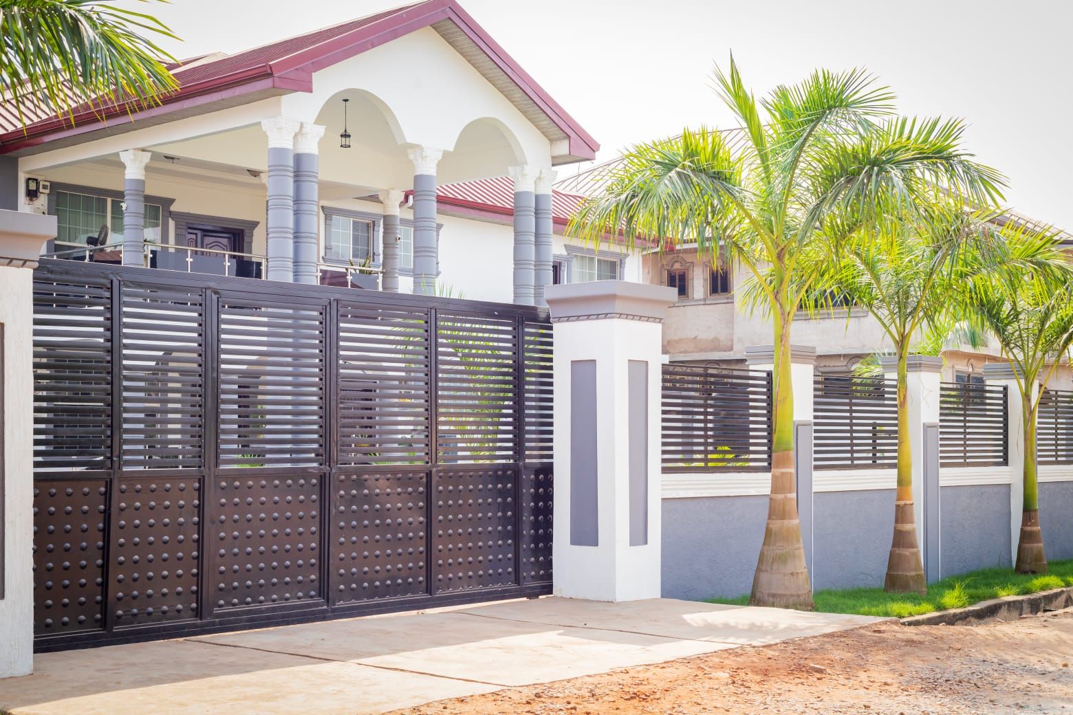 The gated front of Royal Palms Terrace with royal palms along the wall
